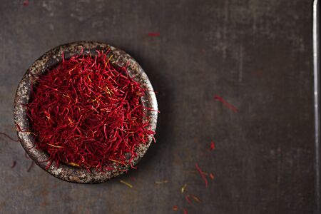 saffron spice threads and powder  in vintage iron dish  old metal background, closeupの写真素材