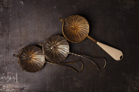 three vintage tea strainers on metal backdrop