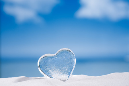 clear glass heart on white sand beach  glitter glass  and reflection ,  sky and seascapeの写真素材