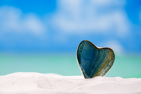 green glass heart on white sand beach,ocean,  sky and seascapeの写真素材
