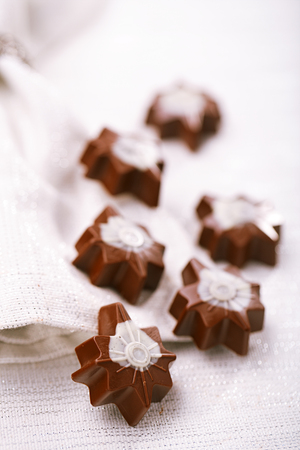 dark chocolate festive christmas star sweets on table with glitter napkinの写真素材