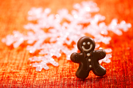 dark chocolate gingerbread man with red christmas backgroundの写真素材