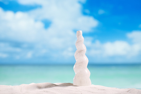 white crystal selenite spiral curved tower on beach sand and seascape backgroundの写真素材