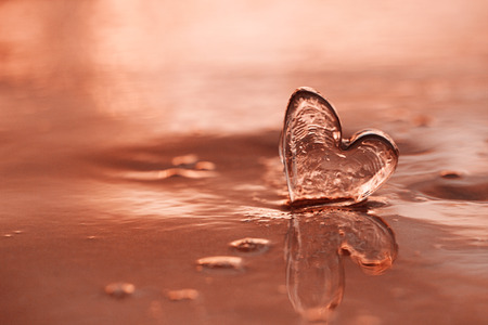 clear glass heart on  sand beach with rose sunrise sun light, Tropical islandの写真素材
