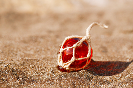 red Glass float on beach sandの写真素材