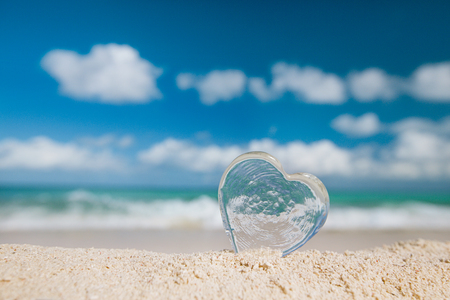 clear glass heart on white sand beach, ocean,  sky and seascapeの写真素材