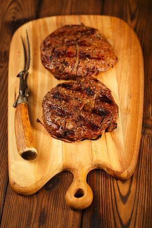 food meat - beef steak on on wooden board with meat forkの写真素材