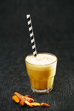 Turmeric latte or golden milk with glitter stars, The drink is made by steaming milk with aromatic turmeric powder and spicesの写真素材