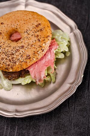 seeded bagel with steak on tin plateの写真素材
