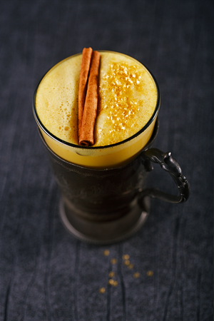 Turmeric latte or golden milk with cinnamon stick , The drink is made by steaming milk with aromatic turmeric powder and spicesの写真素材