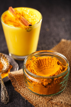 turmeric latte spice mix in small bowl with latte on backgroundの写真素材