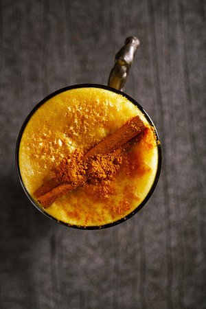 Turmeric latte or golden milk with cinnamon stick , The drink is made by steaming milk with aromatic turmeric powder and spicesの写真素材