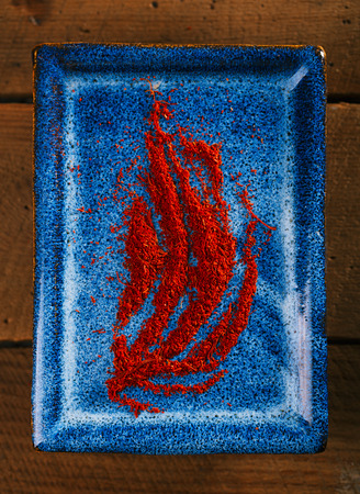 saffron spice powder on blue plate with wood plank backgroundの写真素材