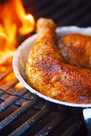 chicken legs spiced by special spice blend on bbq grill with flameの写真素材