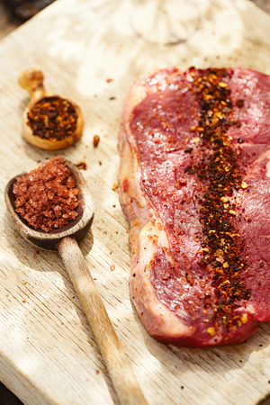 chipotle flakes chilli spice and rose sea salt  with bbq raw beef steak on wooden boardの写真素材