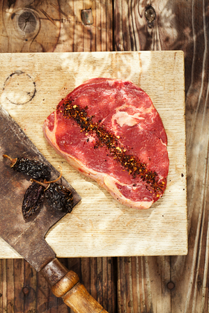 chipotle flakes chilli spice  with bbq raw beef steak on wooden boardの写真素材