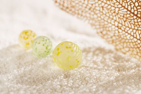 sea glass marbles with corall and shadow on white sand beachの写真素材