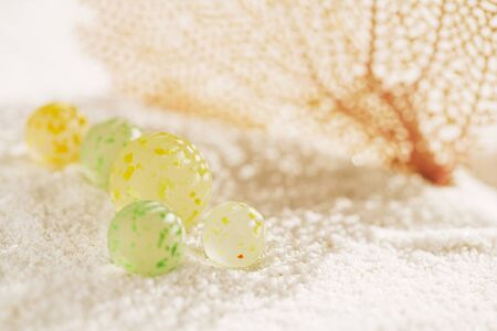 sea glass marbles with corall and shadow on white sand beach with seascapeの写真素材