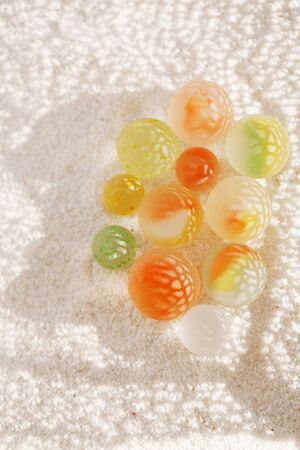 sea glass marbles on white sand beach with corall shadowの写真素材