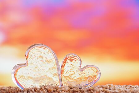 clear heart sea glass  on  beach sand   with bright sunrise or sunset backgroundの写真素材