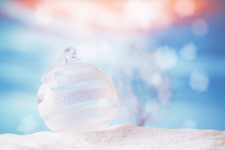 glitter christmas glass bauble  on  beach with seascape backgroundの写真素材