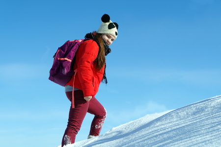 Young beautiful girl in a red jacket and cap panda wanders the snowy placesの写真素材