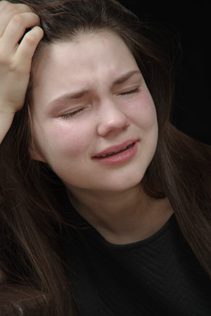Girl suffering from severe depression, crying, tears coming from her eyes.