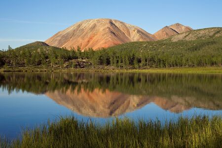 Red Mountain and its reflection in the lake. Oimyakon Highlands. Yakutia. Russia.の写真素材