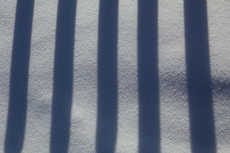 The alternation of light and dark bands. The shadow of the fence in the snow.の写真素材