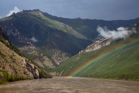 Rainbow above the muddy river in the mountains. The River Indigirka. The Republic Of Sakha. Russia.の写真素材