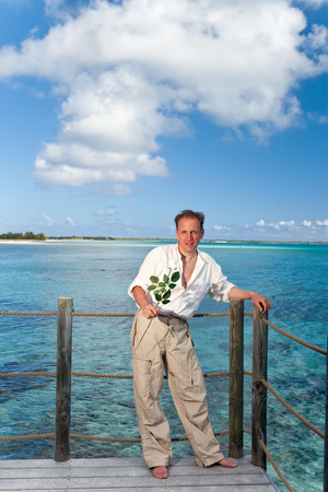 The man in light clothes on a terrace and ocean as a background.の写真素材