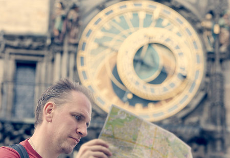 man examines the map on background of historical medieval astronomical Clock on the Old Town Hall in...