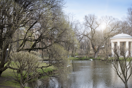 The pavilion on the bank of the lake in the spring park at the beginning of spring, without foliage on treesの写真素材