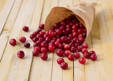 Cranberries in paper bag on yellow wooden backgroundの写真素材