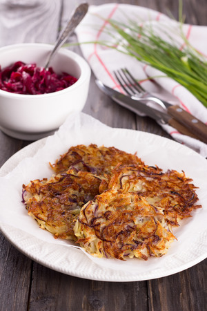 Potato fritters with red onion and spices, beet salad, a bunch of green onions on a wooden surfaceの写真素材