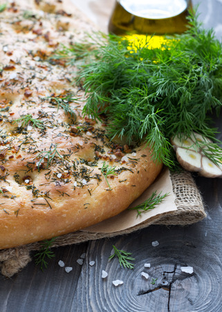 Homemade focaccia with dill, garlic and olive oil on a wooden table in a rustic styleの写真素材