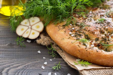 Homemade focaccia with dill, garlic and olive oil on a wooden table in a rustic styleの写真素材