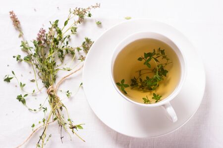 Thyme tea in a white cup on a white napkinの写真素材