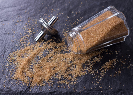 Brown sugar with a glass sugar bowl on the shale backgroundの写真素材