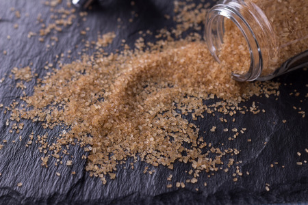 Brown sugar with a glass sugar bowl on the shale backgroundの写真素材