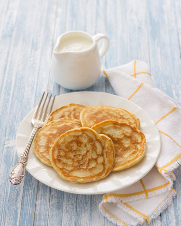 Freshly baked pancakes with sour cream on a light blue background