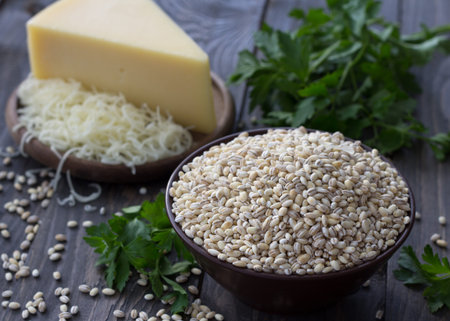 Pearl barley, herbs and cheese, the ingredients for a tasty and healthy breakfast on the wooden tableの写真素材