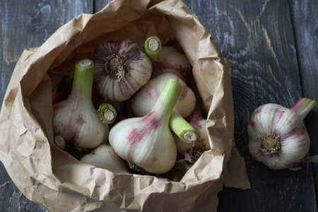 Fresh organic young garlic in paper pack on wooden table, selective focus