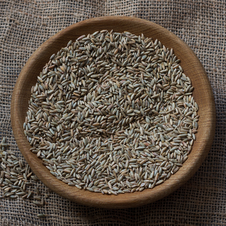 Seeds of rye for germination in a wooden bowl on sackcloth with free spaceの写真素材