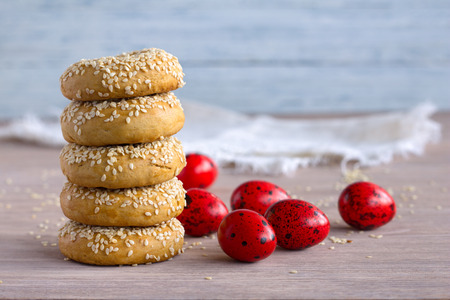 Traditional Greek Easter cookies with sesame seeds and colored eggs on the wooden table, selective focus, free spaceの写真素材