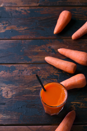 Fresh carrot juice in a glass on a dark wooden background, top view, free spaceの写真素材