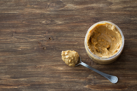 Jar with peanut butter on a wooden table, top view, free spaceの写真素材