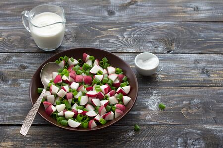 Fresh radish salad with green onions and sour cream on a wooden background, rustic style. Delicious homemade foodの写真素材