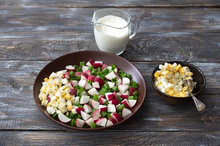 Fresh radish salad with green onions, boiled egg and sour cream on a wooden background, rustic style. Delicious homemade foodの写真素材