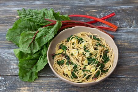 Vegan spaghetti with chard and garlic on a wooden table. Delicious homemade foodの写真素材